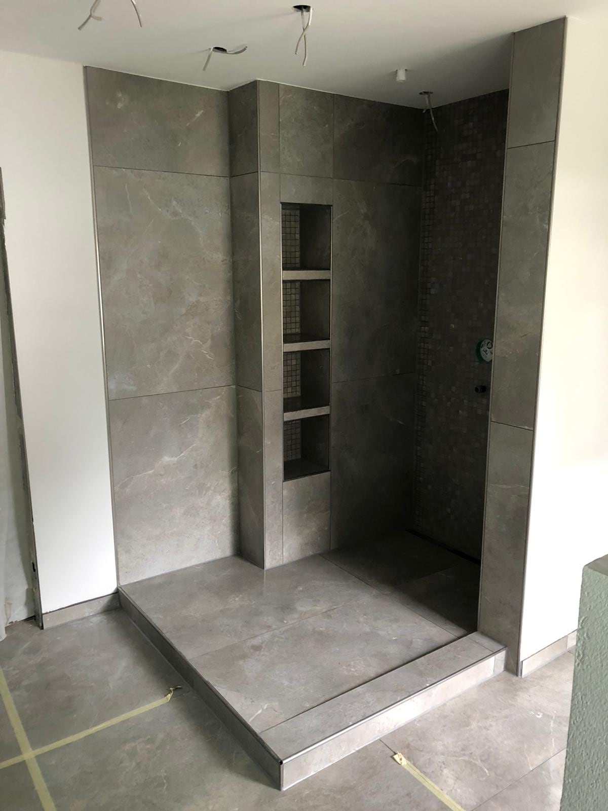 Bodengleiche Dusche mit großformatigen grauen Fliesen und Wandnischen